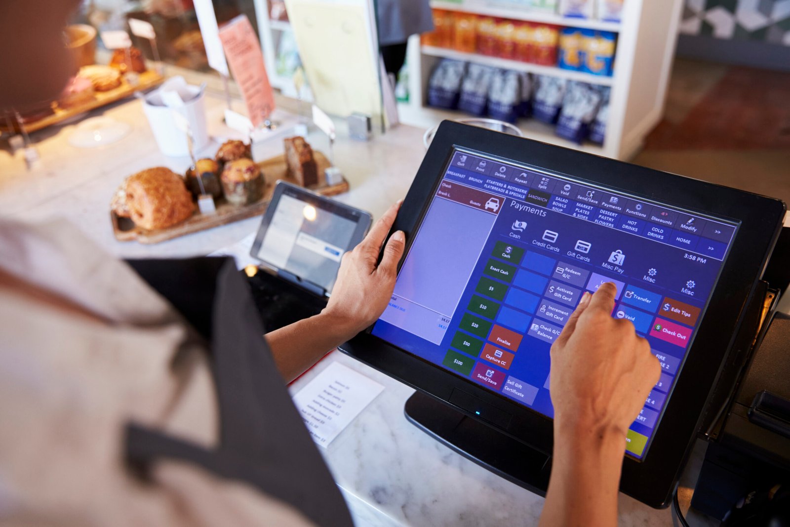 Employé à un café en train de manipuler un terminal de vente ou POS